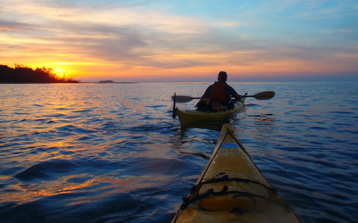 two kayaks are paddled into the sunset on an outward bound veterans expedition 